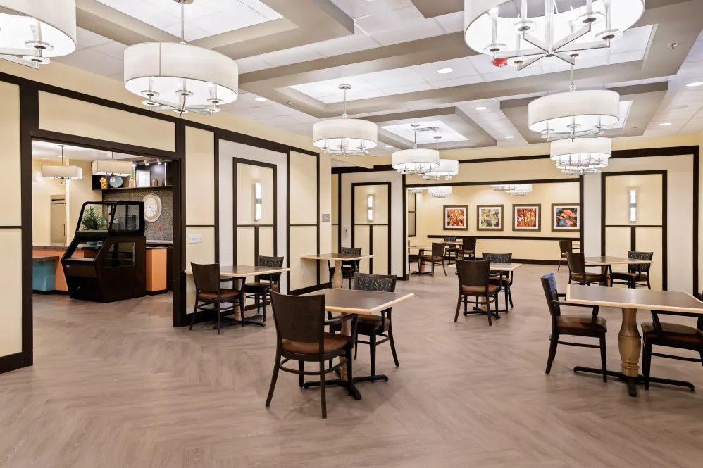A spacious and elegantly decorated dining area with multiple tables and modern chandeliers.