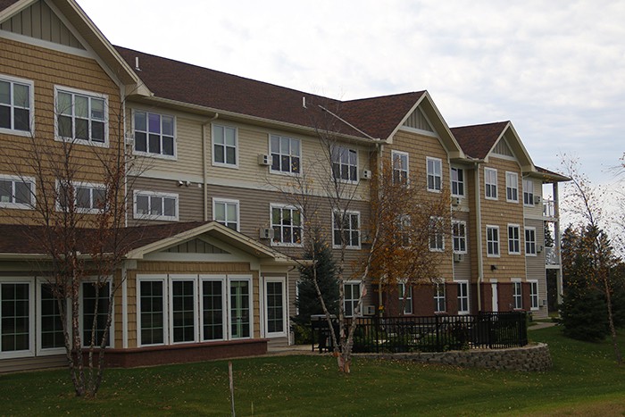A multi-story residential building with a landscaped front lawn.