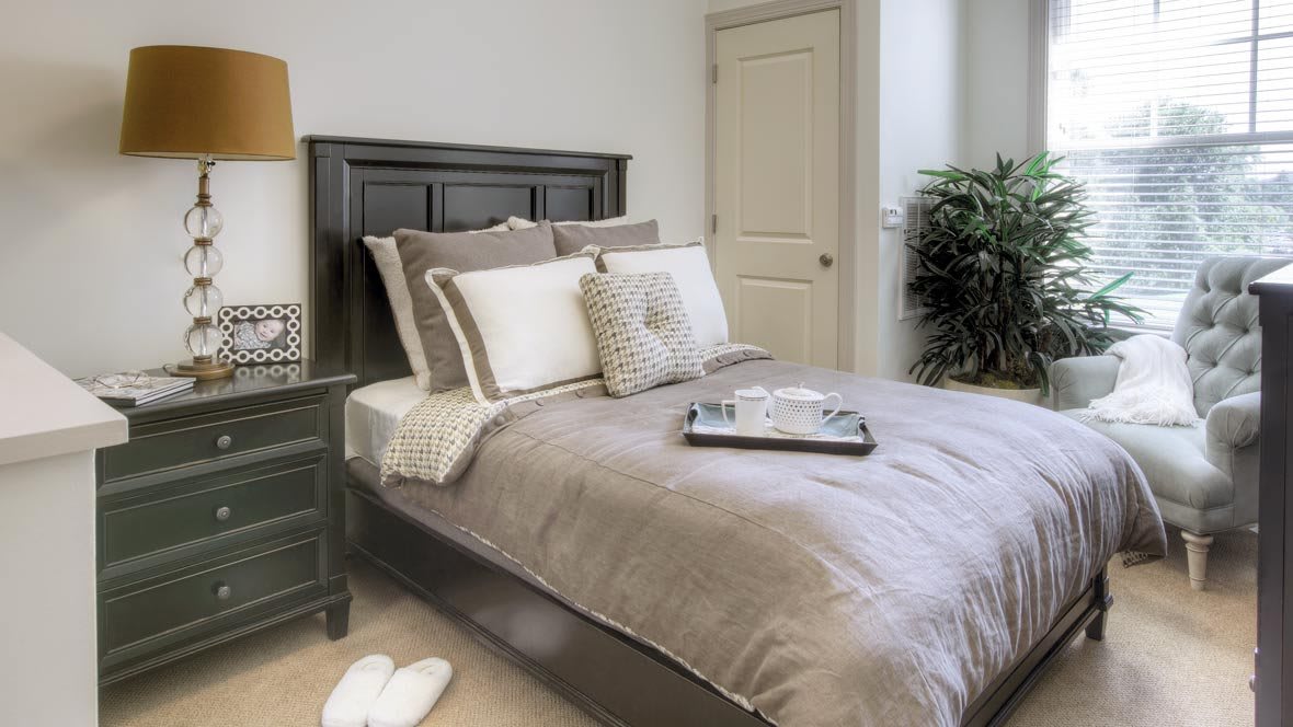 A cozy bedroom with a neatly made bed, pillows, and a bedside table.