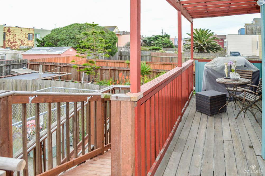 A wooden deck with railing overlooking a backyard.