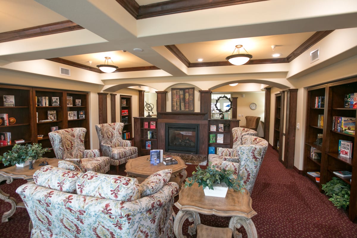 A cozy lounge area with comfortable seating and a fireplace, surrounded by bookshelves.