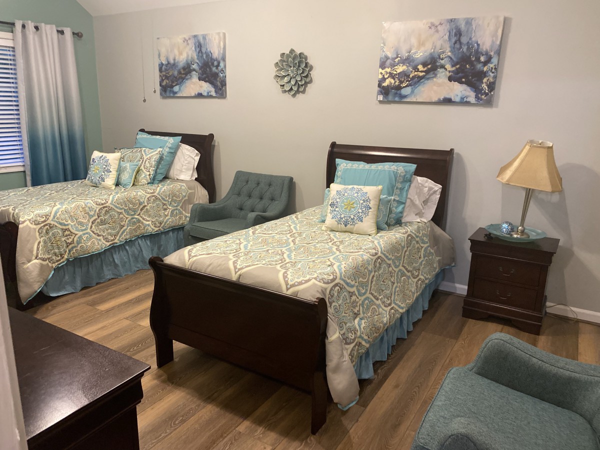 A neatly arranged bedroom featuring two twin beds with coordinated bedding and artwork on the walls.