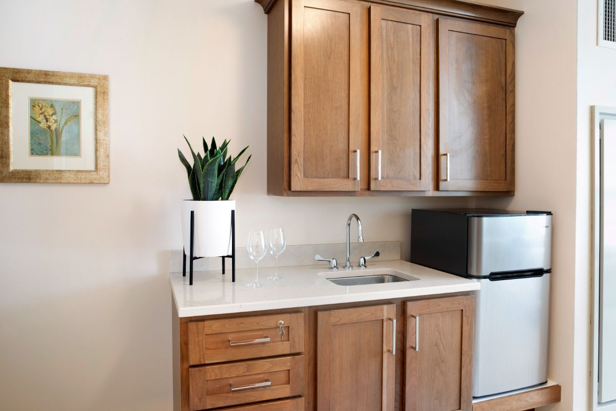 A modern kitchen setup featuring wooden cabinets, a small sink, and a mini fridge.