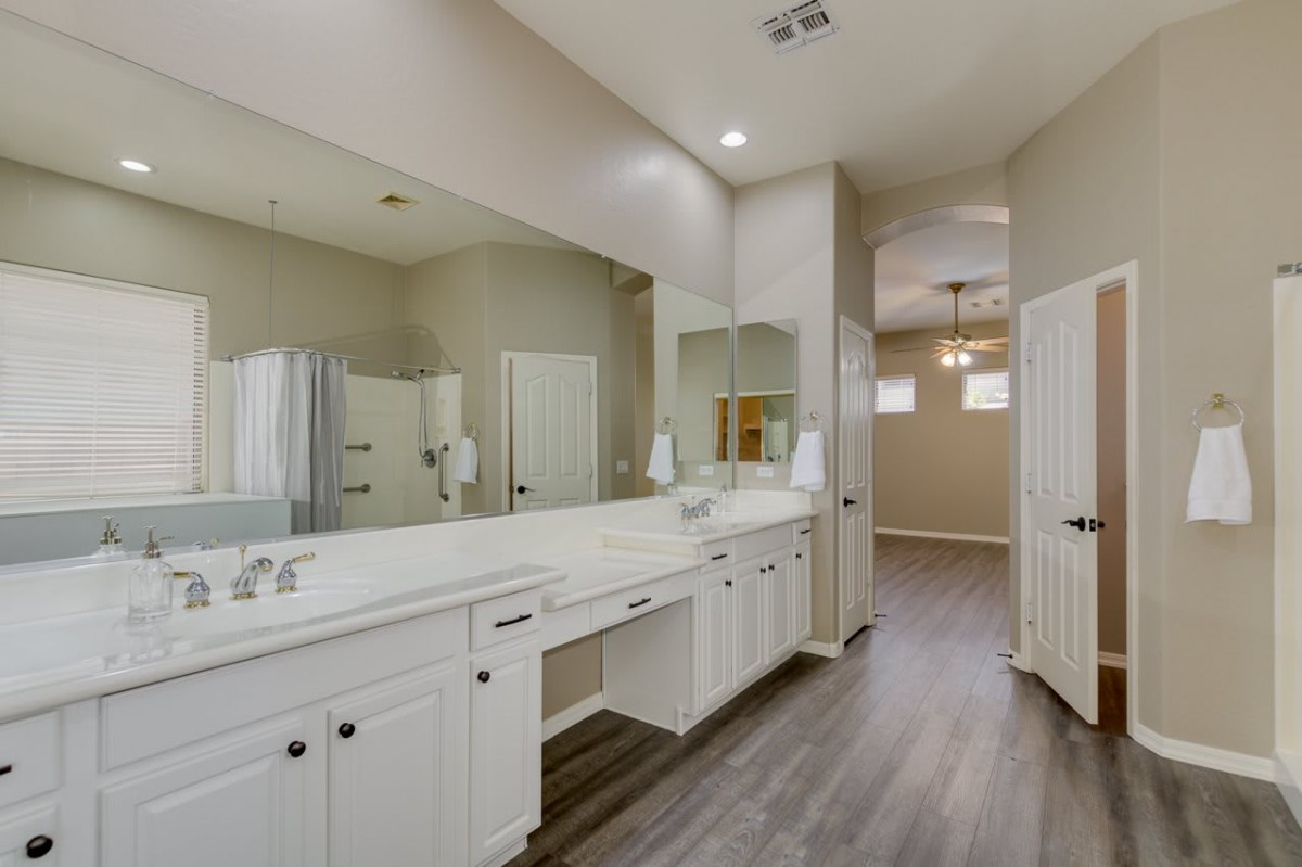 A modern bathroom interior with a double sink vanity and hardwood floors.
