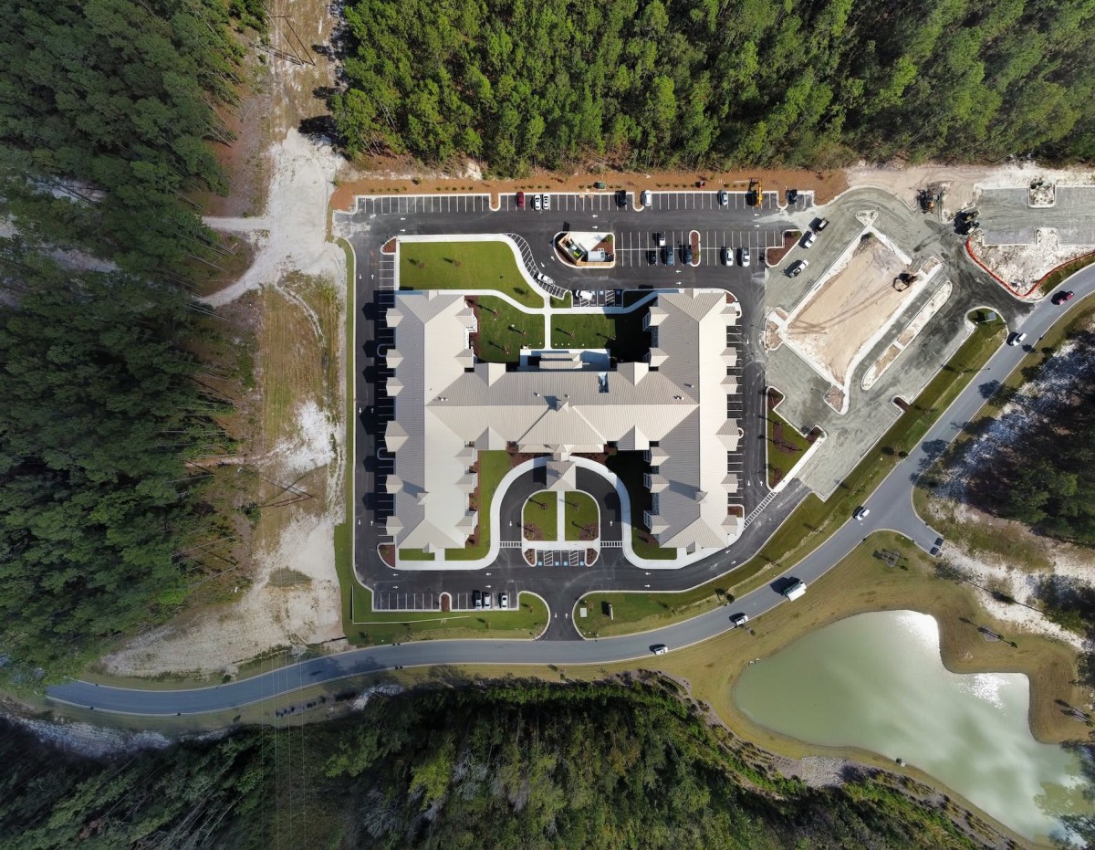 Aerial view of a large building complex surrounded by trees and roads.