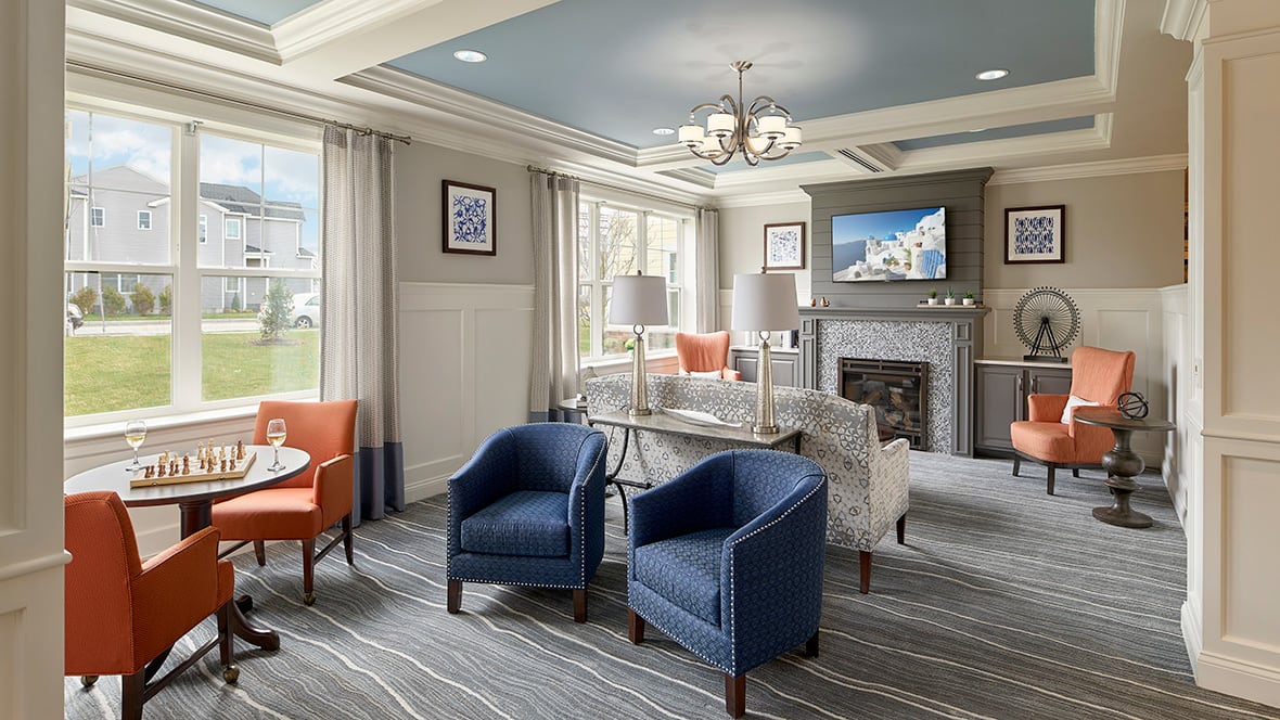 A modern living room with blue armchairs, a fireplace, and elegant decor.
