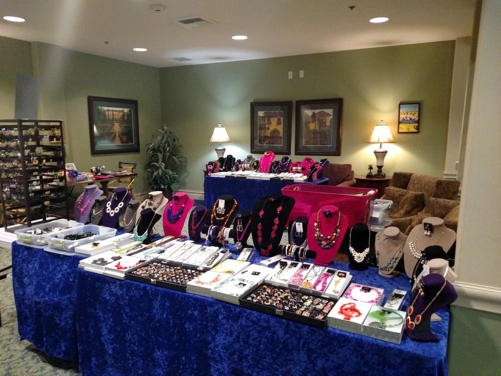 An indoor market setup featuring a variety of jewelry including necklaces, earrings, and bracelets displayed on velvet-covered tables.