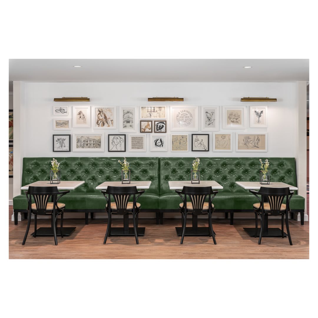 A stylish restaurant interior featuring green upholstered seating and eclectic wall decor.