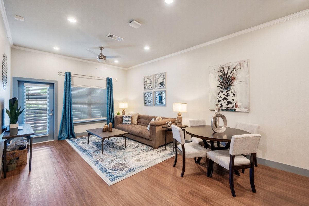 A modern living room with stylish decor, featuring a comfortable sofa, wooden flooring, and elegant artwork.