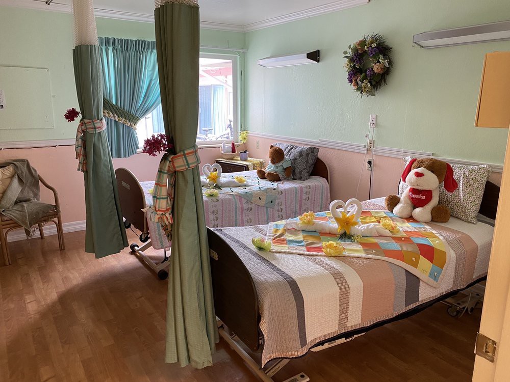 A cozy hospital room with two beds, decorative curtains, and a stuffed animal placed on one bed.