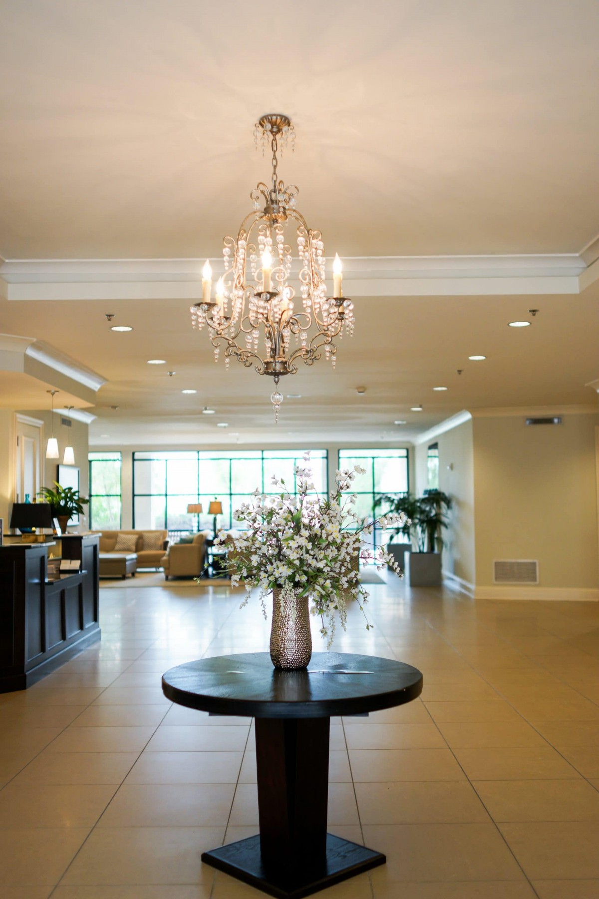 A spacious lobby with a chandelier and floral arrangement on display.