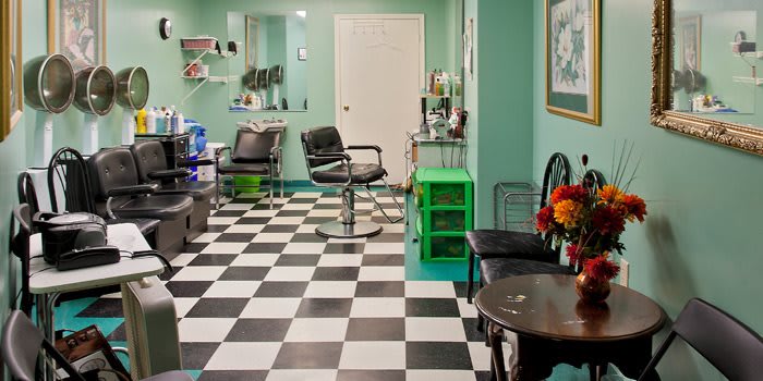 An empty barber shop with black and white checkered flooring and stylish furniture.