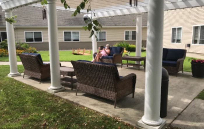 People relaxing on a patio under a pergola.