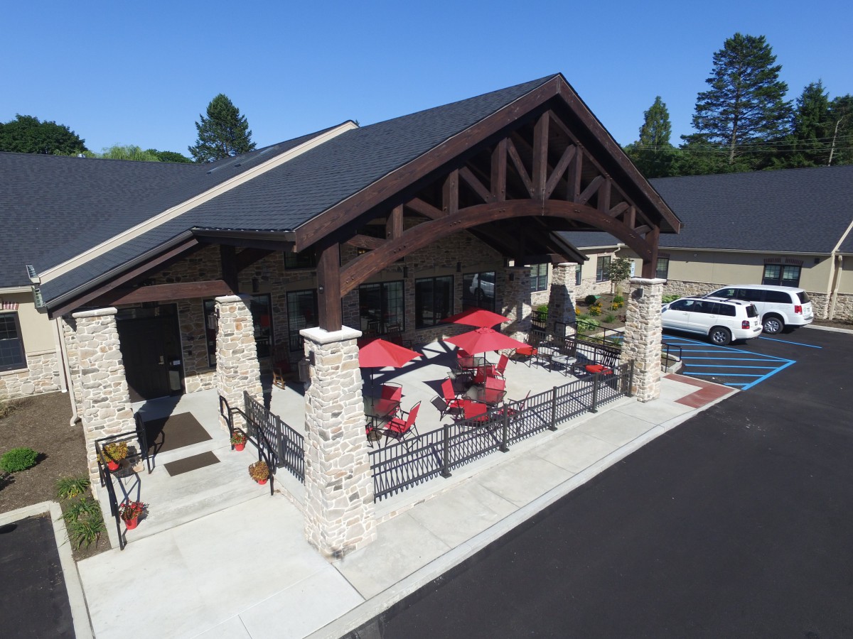Aerial view of a building with a covered patio featuring red umbrellas and stone pillars.