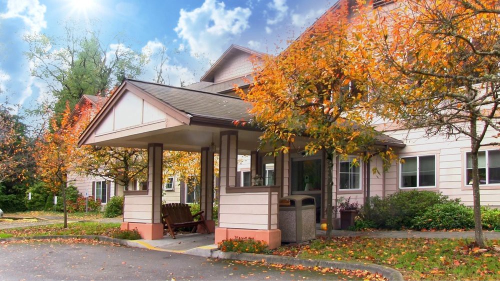 A building entrance surrounded by vibrant autumn trees under a blue sky.