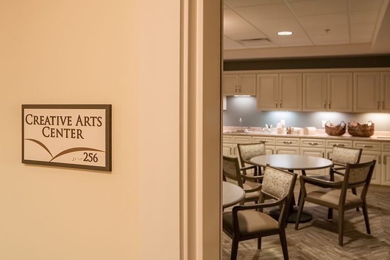 A view into a room labeled 'Creative Arts Center' with tables and chairs arranged inside.