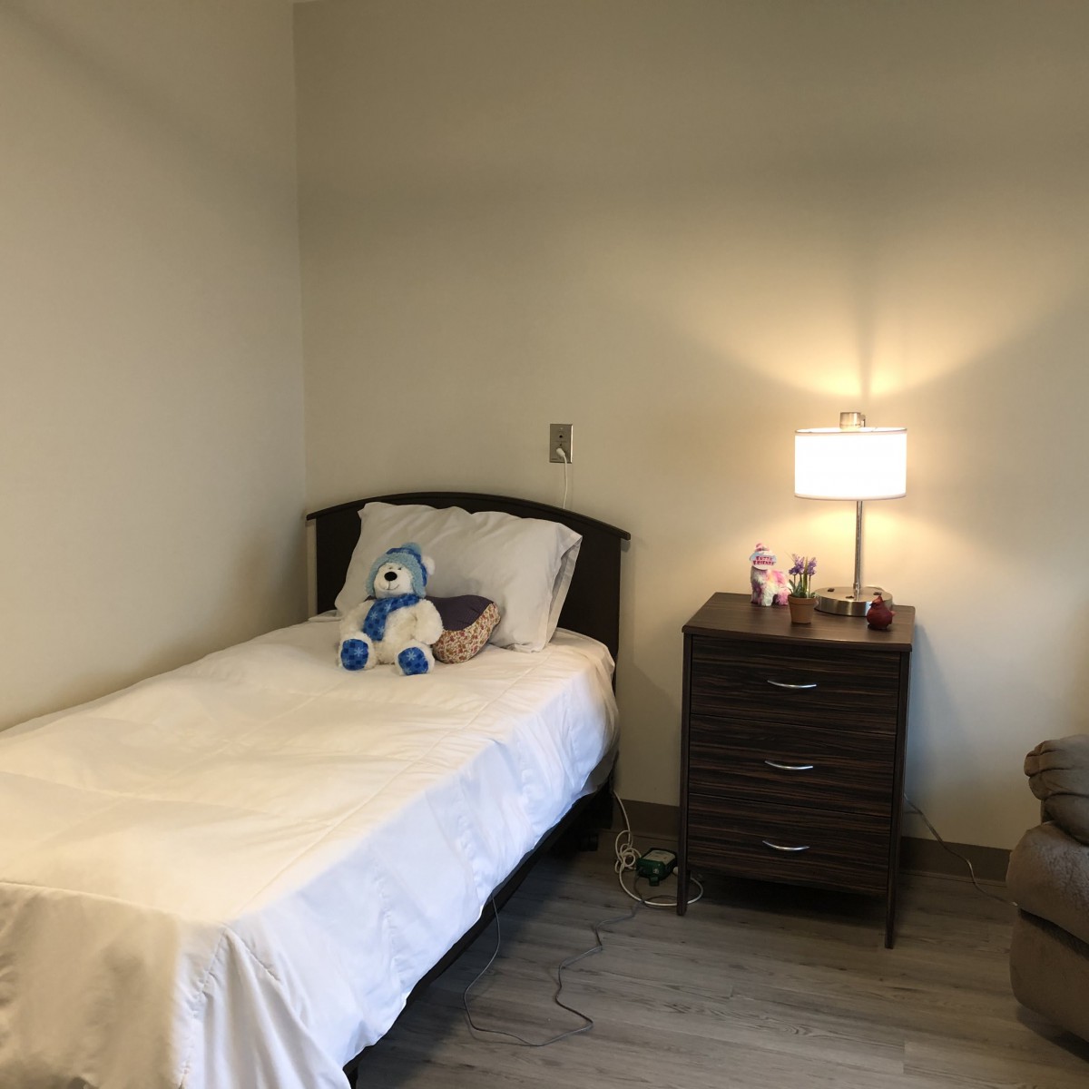 A minimalist bedroom with a single bed, nightstand, and lamp.