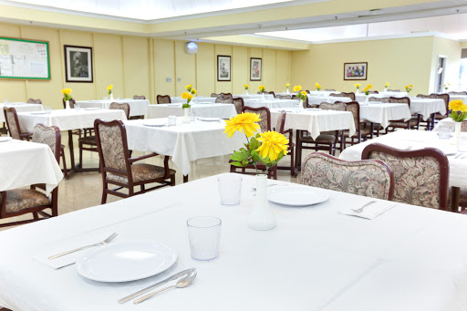 A well-set dining room featuring tables with white tablecloths and vibrant yellow flowers.