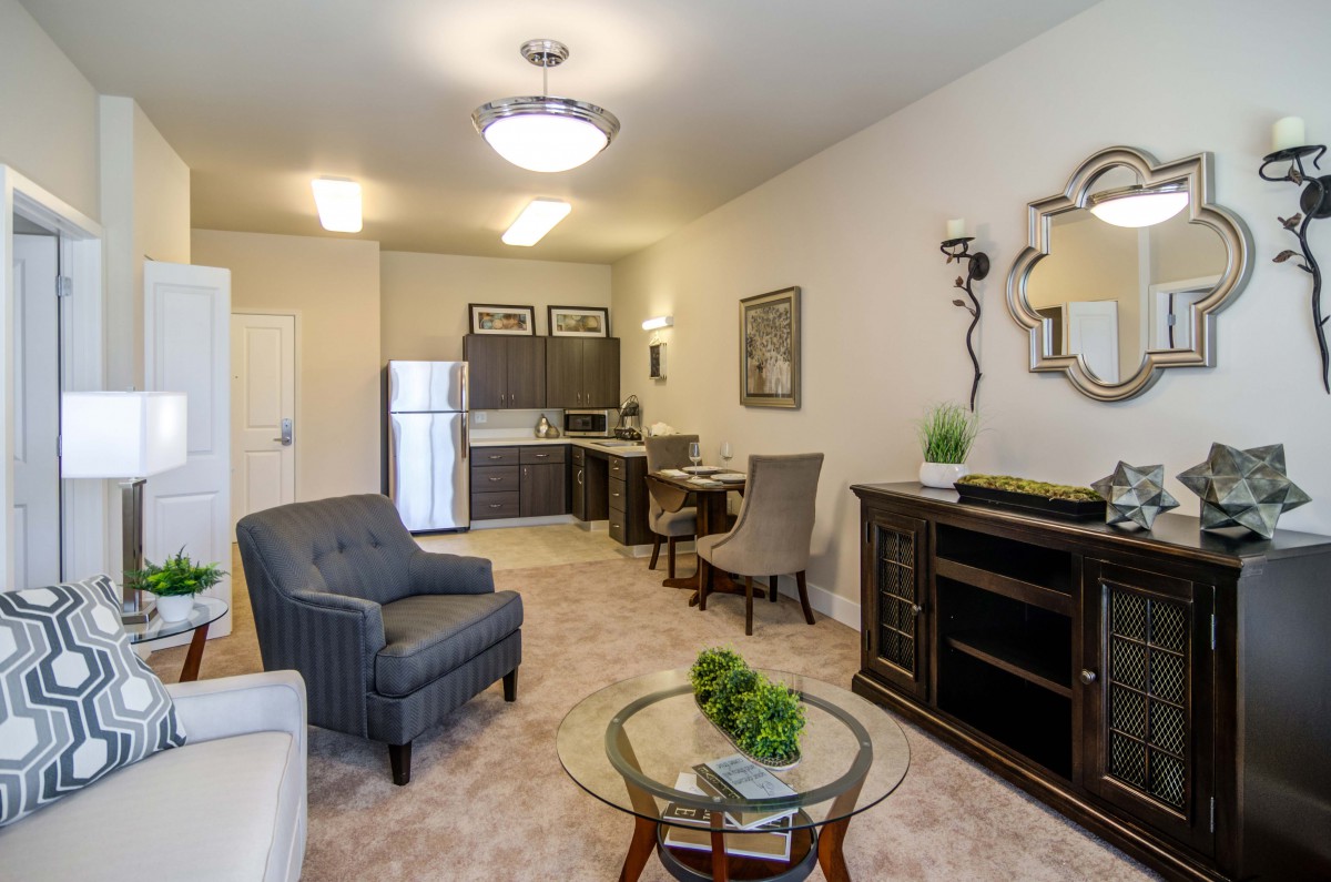 A modern apartment living room with an open kitchen, featuring stylish furniture and elegant decor.