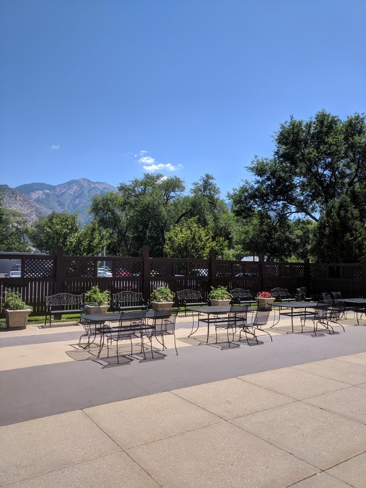 An inviting patio area with outdoor seating, surrounded by lush greenery and a scenic mountain backdrop under a clear blue sky.