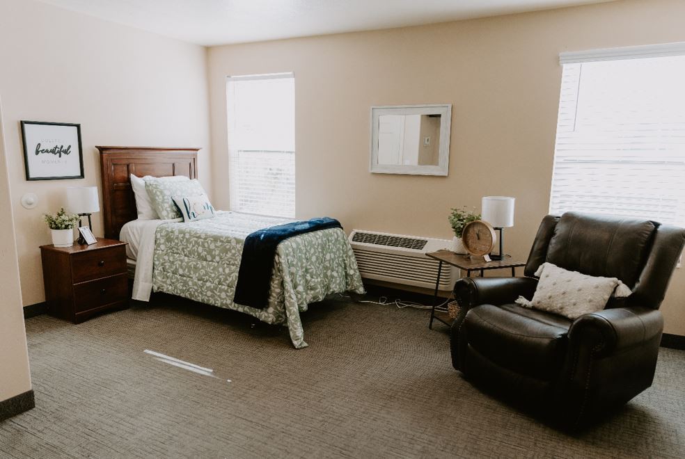 A cozy bedroom with a bed, armchair, and decorative elements.