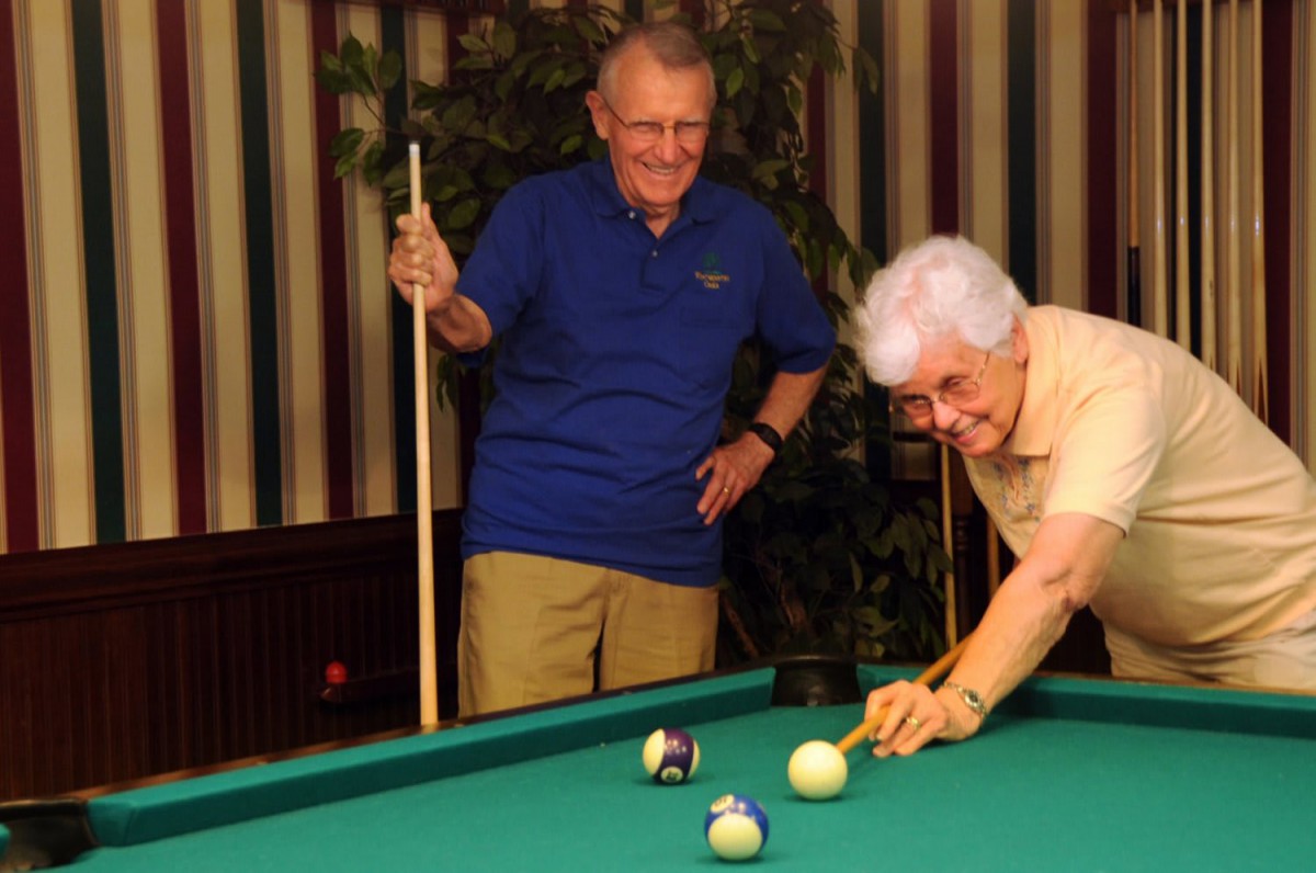 Two seniors enjoying a game of pool.