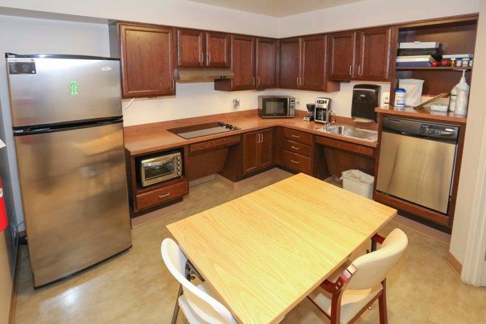 A kitchen with wooden cabinets, a central table, and various appliances including a microwave and refrigerator.