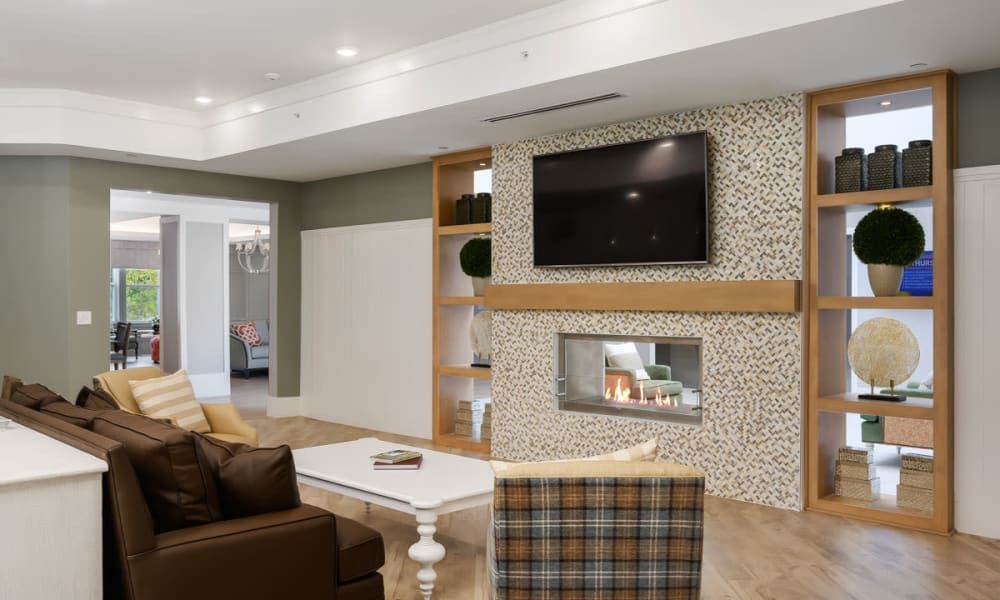A modern living room with a cozy fireplace, wall-mounted TV, and stylish seating area.