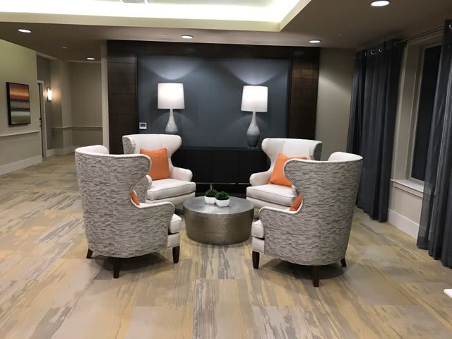 A modern lounge area with four patterned chairs arranged around a round table, accompanied by soft lighting and decorative accents.