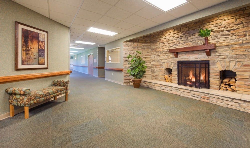 A cozy hallway with a stone fireplace, carpeted flooring, and seating area.