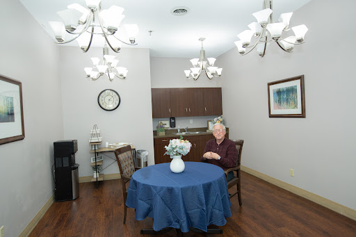 A cozy indoor space featuring a blue table with flowers and a person seated in a well-lit room.