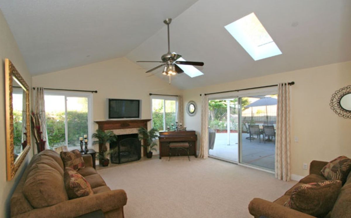 A spacious living room with a fireplace, television, and sliding glass doors leading to a patio.