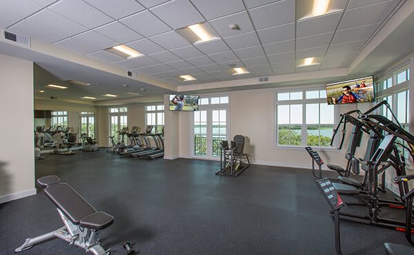 A spacious gym with exercise equipment and large windows.