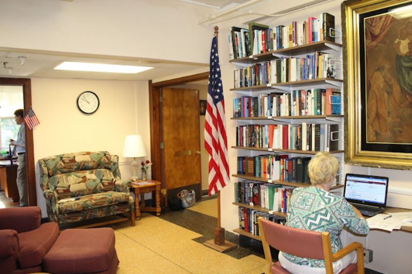 A cozy library corner with a bookshelf, an American flag, and seating areas.