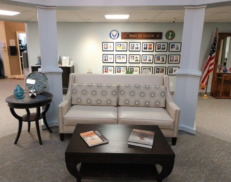 A comfortable lounge area featuring a patterned couch, coffee table with magazines, and framed photos on the wall.