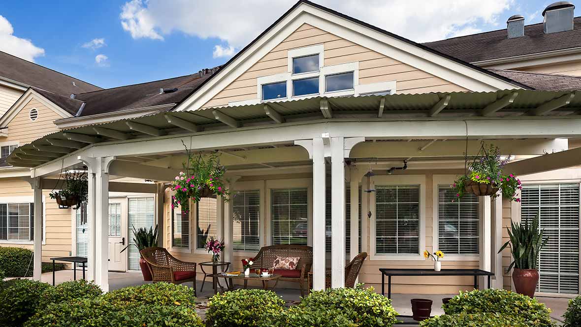 A cozy house with a welcoming porch featuring comfortable outdoor seating and hanging plants.