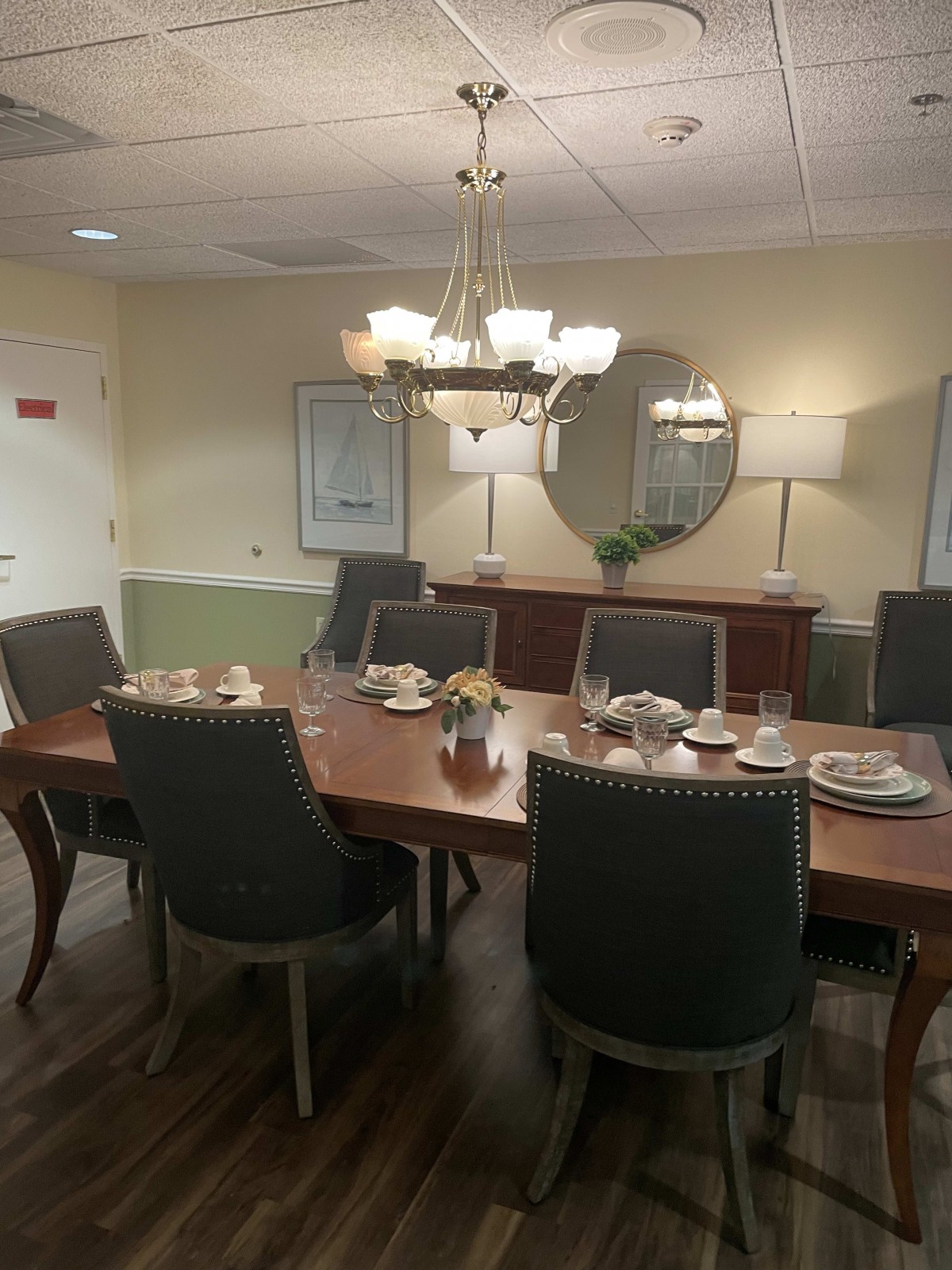 A well-set dining room with an elegant chandelier and mirror.