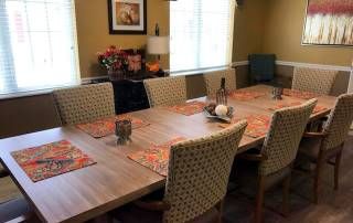A cozy dining room setup with a wooden table and patterned chairs, adorned with colorful placemats.