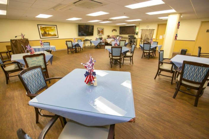 A well-lit dining area with multiple tables and chairs, decorated for a communal gathering.