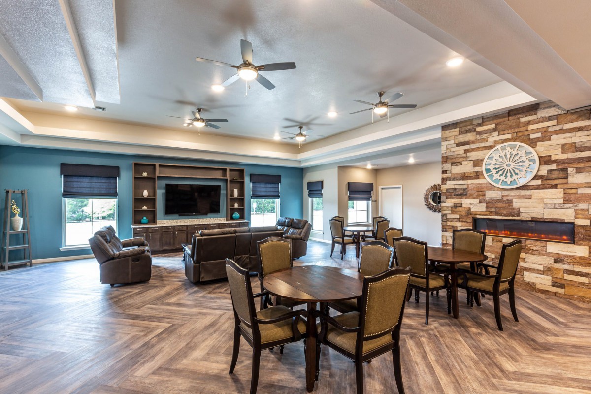 A modern living room featuring a spacious seating area with ceiling fans, a large television, and stylish decor.