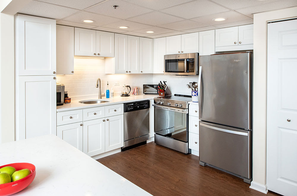 A modern kitchen with white cabinets and stainless steel appliances.