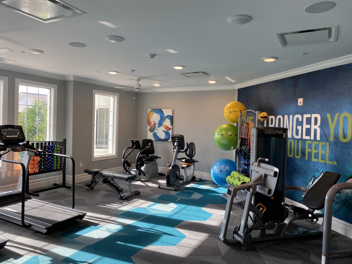 A well-equipped gym with treadmills, stationary bikes, and other exercise equipment in a brightly lit room.