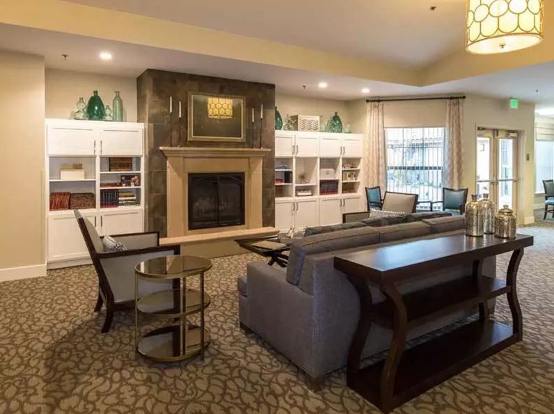 A cozy living room with a fireplace, elegant furniture, and built-in shelves.