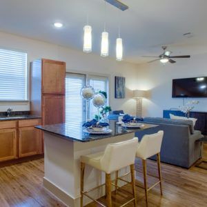 A modern open-concept kitchen and living room with an island counter and wood flooring.