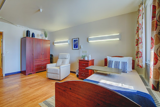 A modern and cozy room featuring a bed, comfortable chair, and elegant lighting.