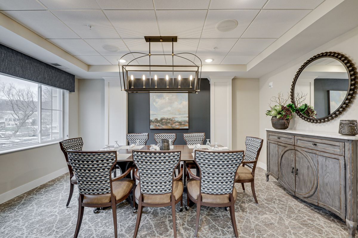 A modern dining room featuring a large table surrounded by elegant chairs, a striking chandelier, and tasteful artwork on the wall.