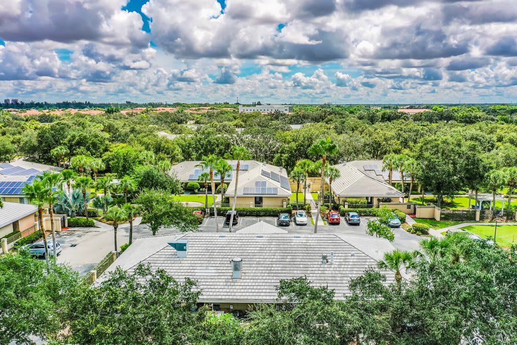 Aerial view of a suburban neighborhood with houses surrounded by greenery under a cloudy sky.