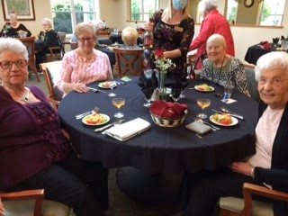 A group of elderly individuals enjoying a meal together at a dining table.