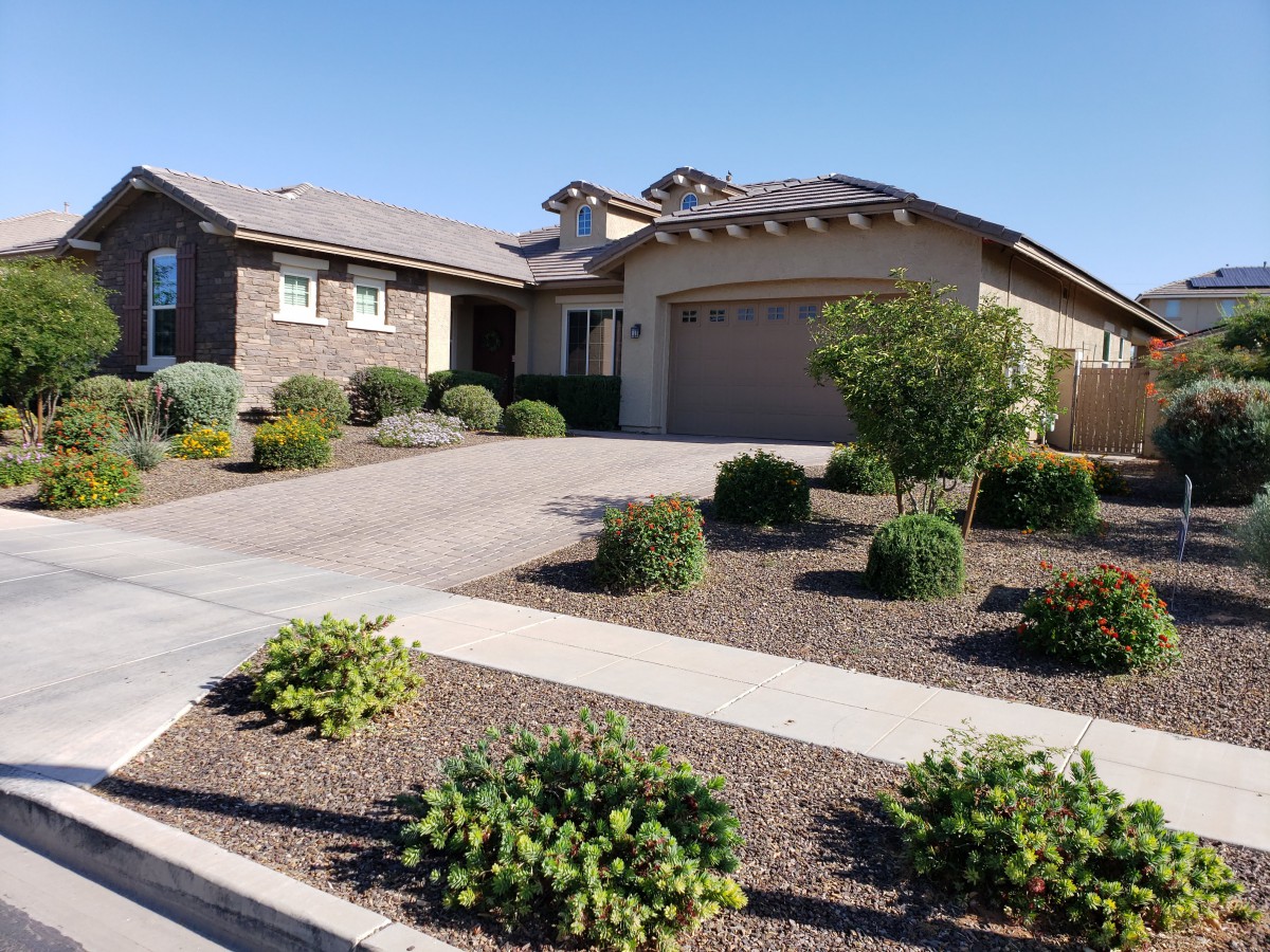 A suburban house with well-maintained landscaping and a driveway on a sunny day.