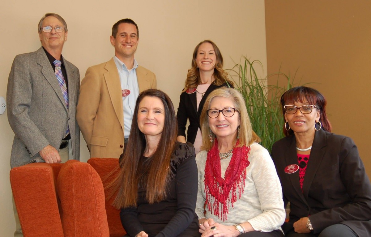 A group of people posing together in an office setting.